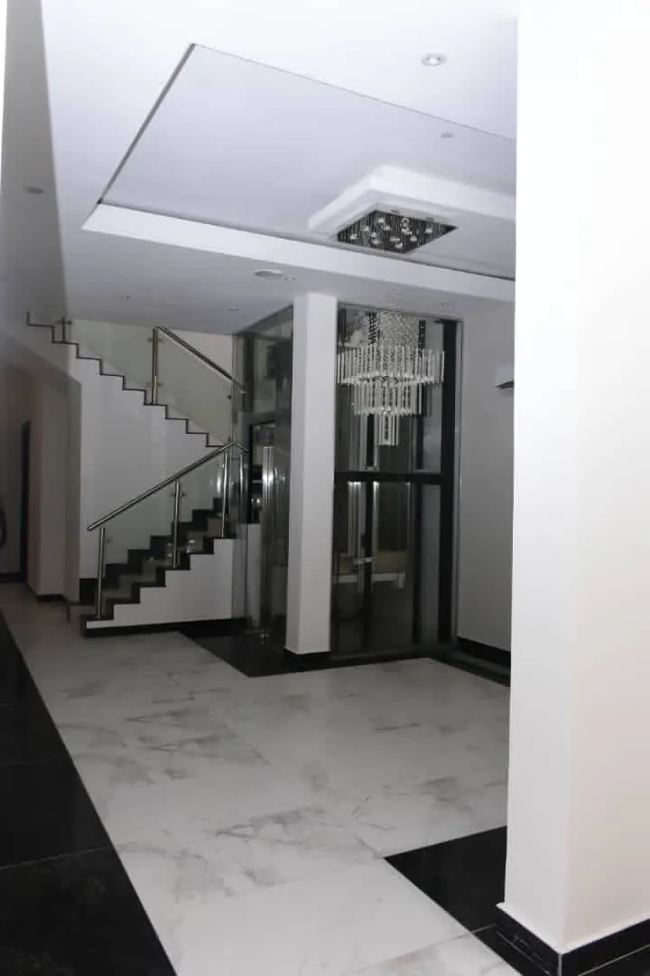 Finished lobby in a Mindfire residence, with a glass-balustrade staircase and a passenger lift