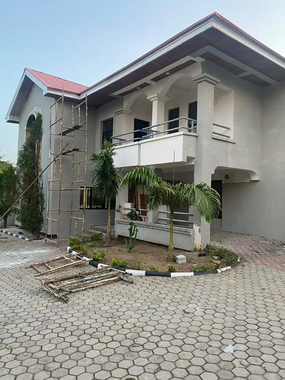 Two-storey residence with arched balconies being rendered, ladders against the wall
