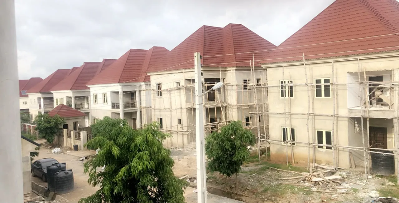 Row of terraced houses with red tiled roofs, rendering in progress behind scaffolding