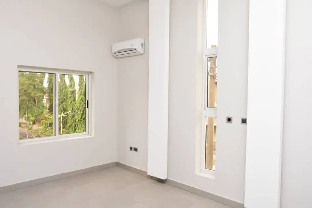 Finished bedroom with tall windows, split-unit air conditioning, and tiled floor