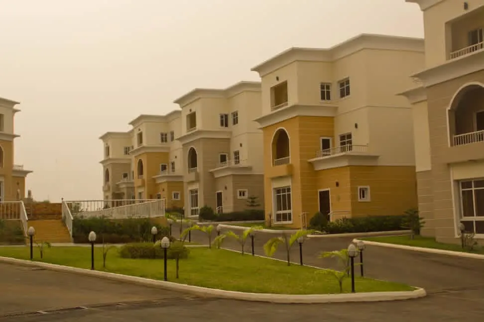 Completed estate street lined with three-storey villas, lawns, and lamp posts