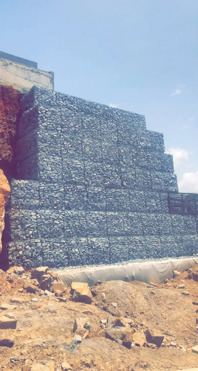 Stepped gabion retaining wall built against a cut slope