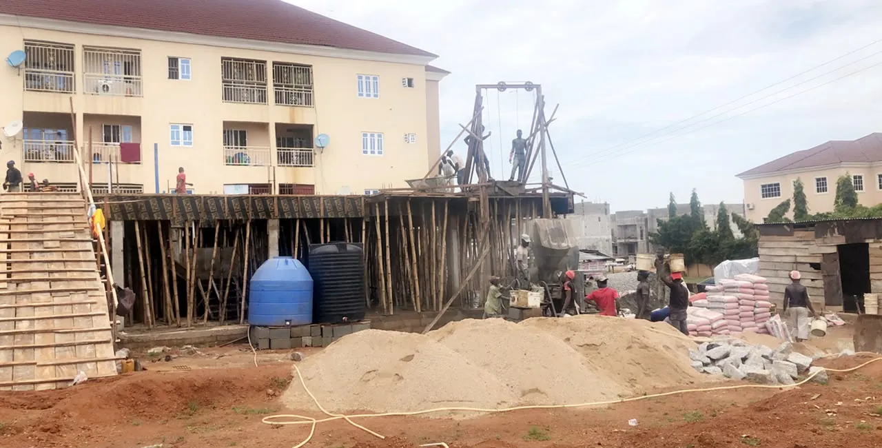 Site crew carrying concrete during a slab pour, with a hoist and propped formwork